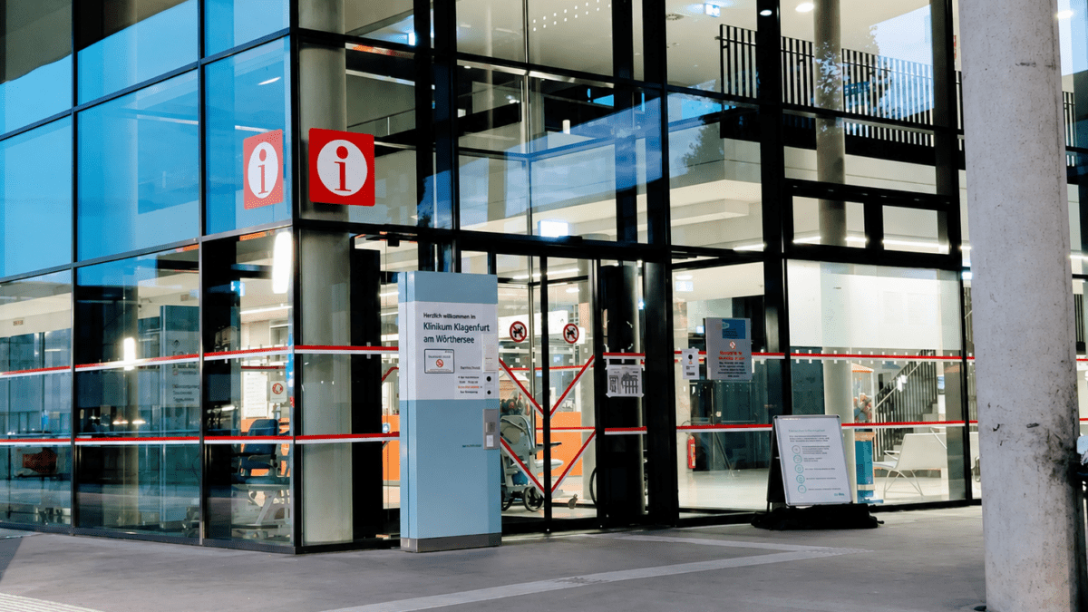 Eingang des Klinikums Klagenfurt am Wörthersee mit Glasfassade und roten Absperrbändern