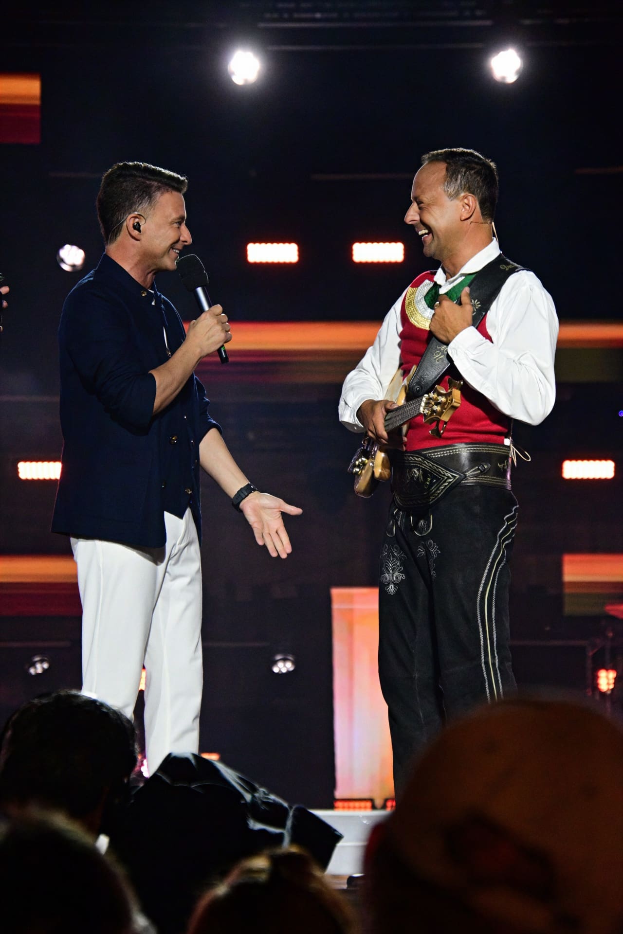 Zwei lächelnde Männer auf der Bühne beim Sommer Open Air, einer mit Mikrofon und einer mit Gitarre.