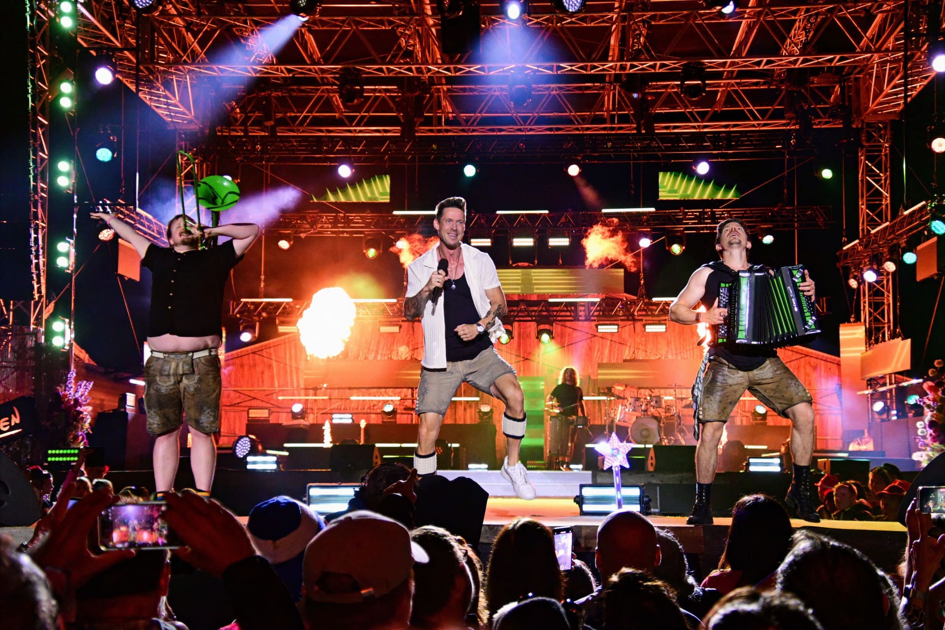 Drei Musiker performen auf einer beleuchteten Bühne beim Sommer Open Air vor Publikum