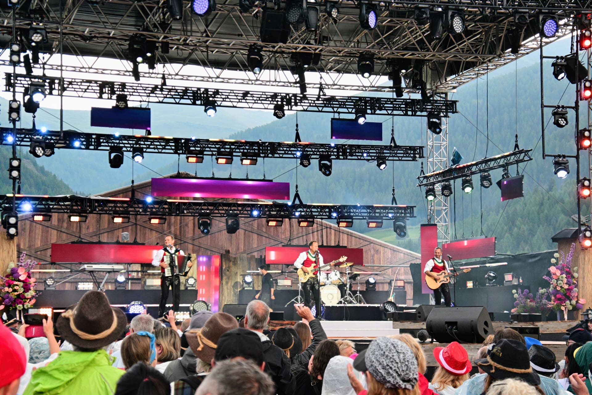 Drei Musiker mit Akkordeon und Gitarren auf einer großen Open-Air-Bühne vor Publikum