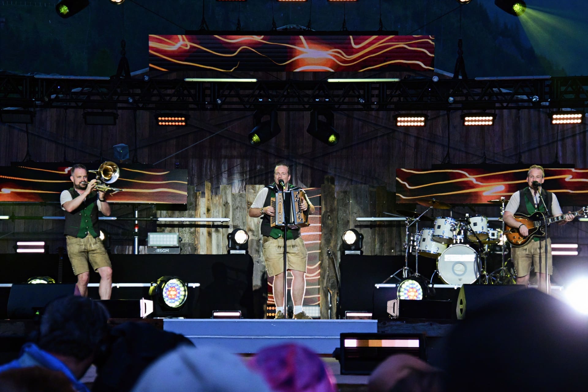 Drei Musiker in Tracht auf einer Bühne beim Sommer Open Air mit Trompete, Akkordeon und Gitarre