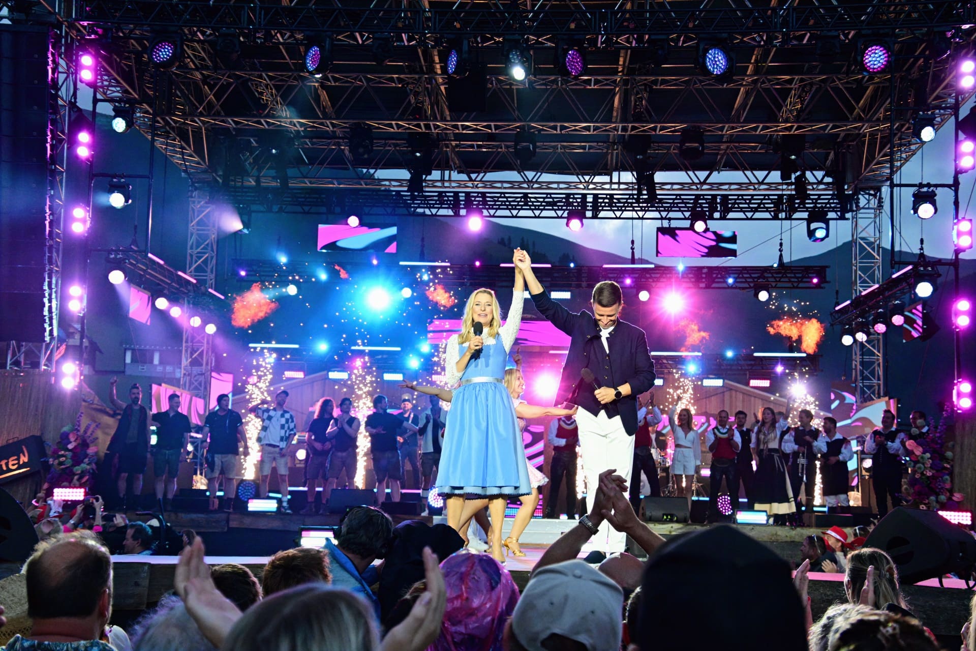 Stefanie Hertel und Marco Ventre stehen Hand in Hand auf einer beleuchteten Open-Air-Bühne vor applaudierendem Publikum