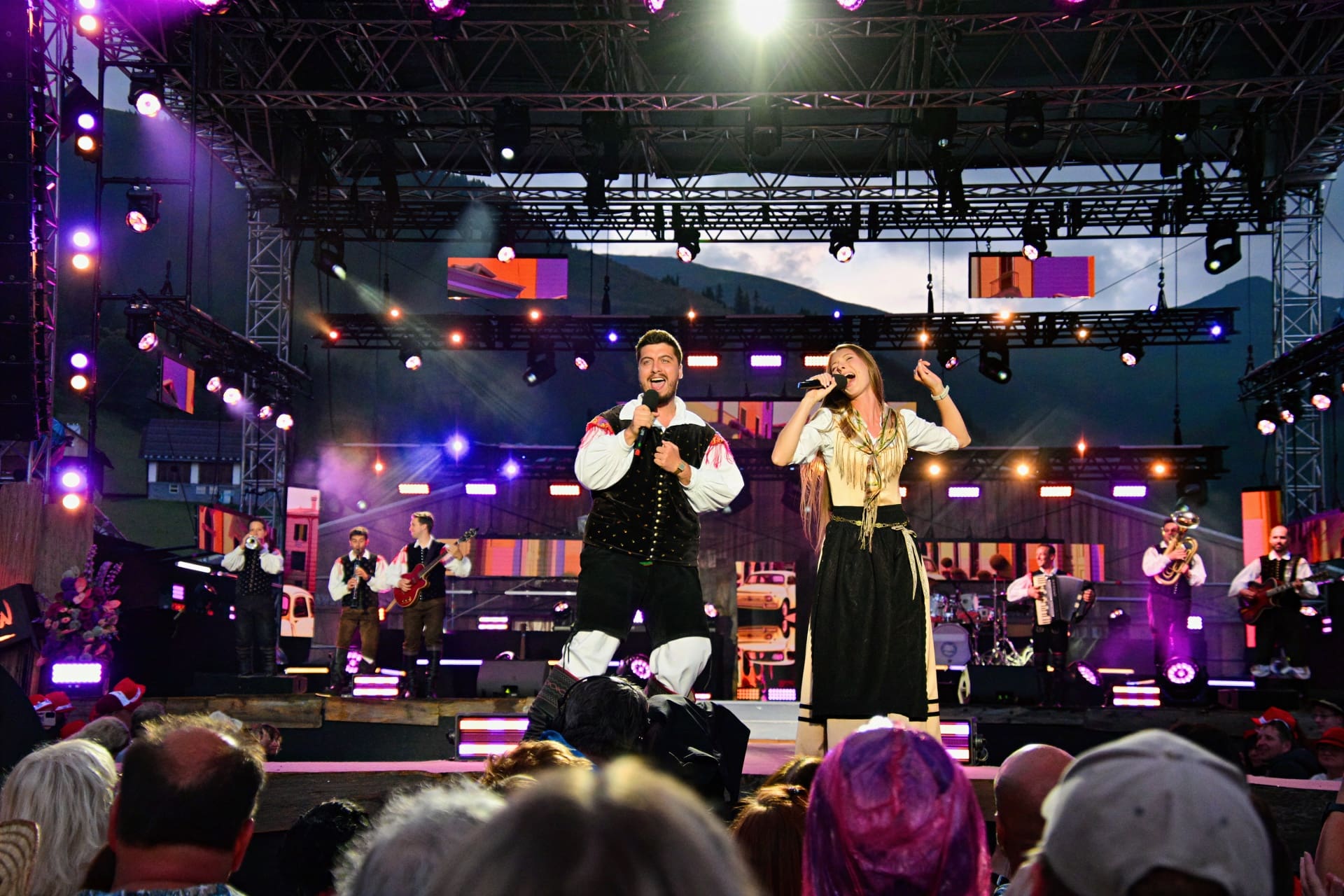 Sänger und Sängerin in Tracht auf beleuchteter Bühne beim Open Air
