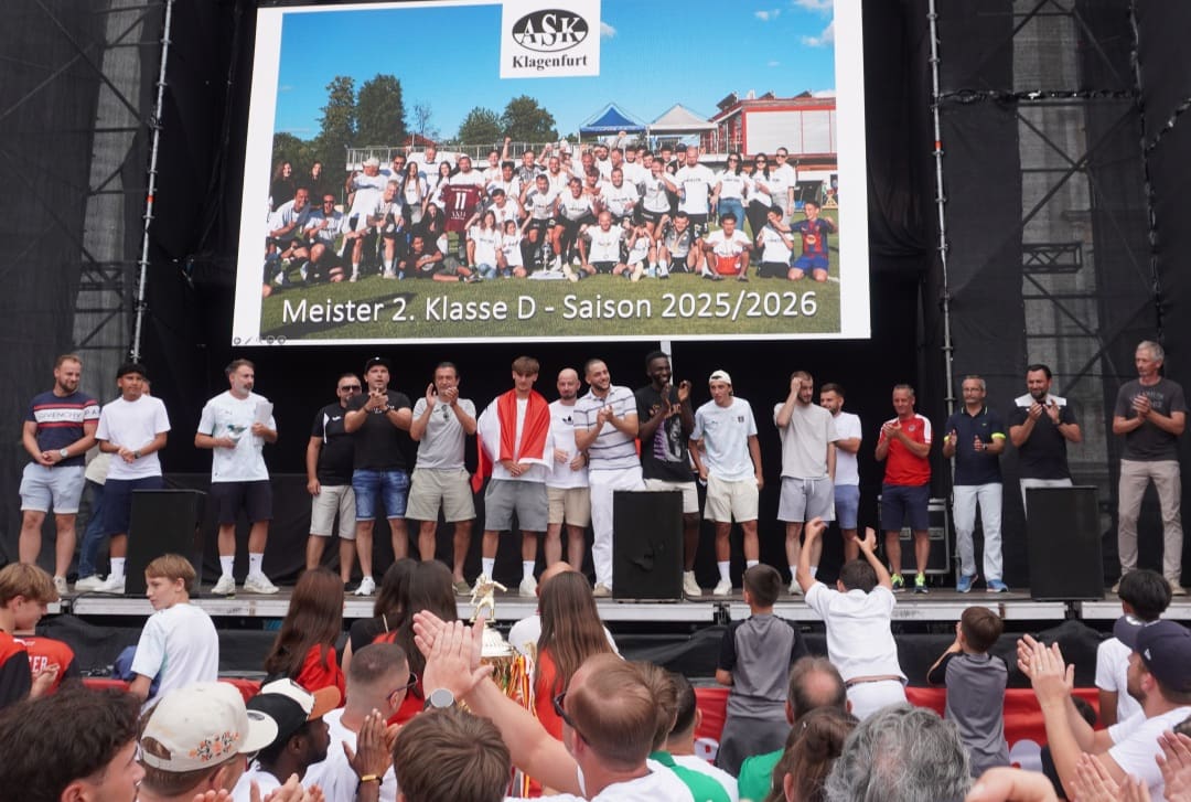 Männer stehen auf einer Bühne und applaudieren vor einer Leinwand mit dem Meisterfoto des ASK Klagenfurt