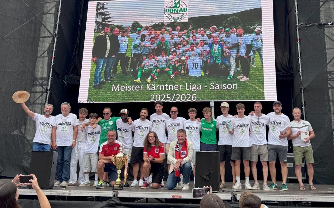 Gruppe von Menschen auf einer Bühne vor einer Leinwand mit SV Donau Mannschaft und Meistertitel