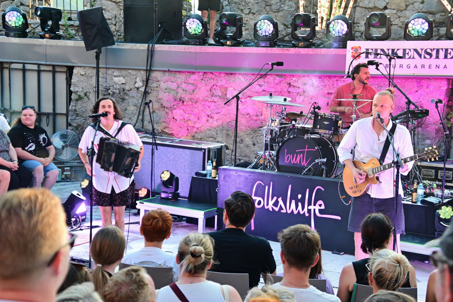 Zwei Musiker der Band Folkshilfe auf der Bühne mit Akkordeon und Gitarre vor Publikum