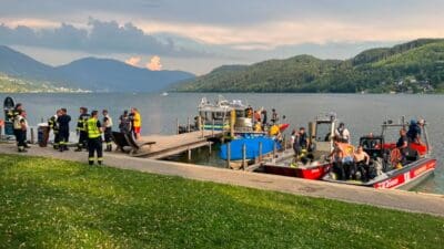 Einsatzkräfte und Boote stehen am Steg am Millstätter See