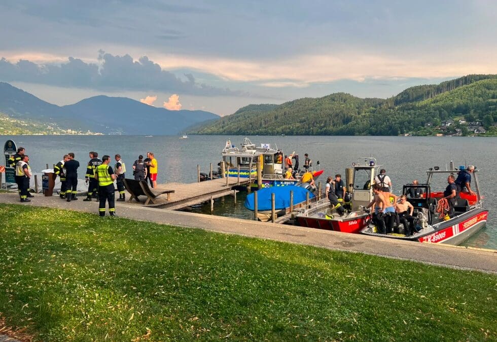 Einsatzkräfte und Boote stehen am Steg am Millstätter See