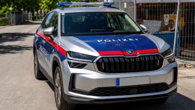 Silbernes Polizeiauto mit Blaulicht und rot-blauer Lackierung vor Baustelle