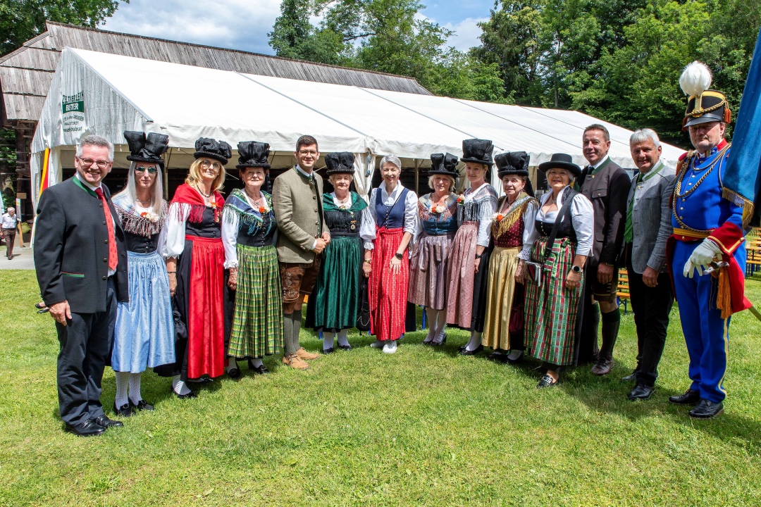 Gruppe von Menschen in traditionellen Kärntner Trachten vor einem weißen Zelt auf einer Wiese