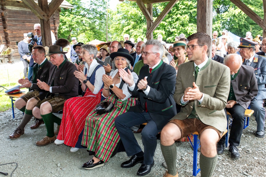 Menschen in traditioneller Kärntner Tracht applaudieren sitzend bei einer Veranstaltung