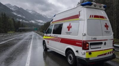 Weißer Rettungswagen des Österreichischen Roten Kreuzes auf nasser Autobahn vor Bergkulisse