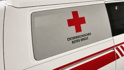 Seitenansicht eines weißen Rettungsfahrzeugs mit dem Logo des Österreichischen Roten Kreuzes