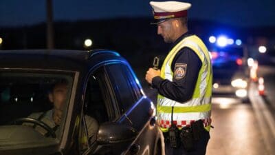 Polizist der Bundespolizei in Warnweste kontrolliert Autofahrer bei nächtlicher Verkehrskontrolle