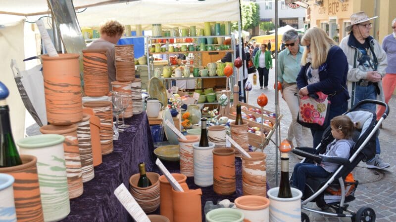 Marktstand mit bunten Keramikvasen und Töpfen auf violetter Tischdecke in der Altstadt
