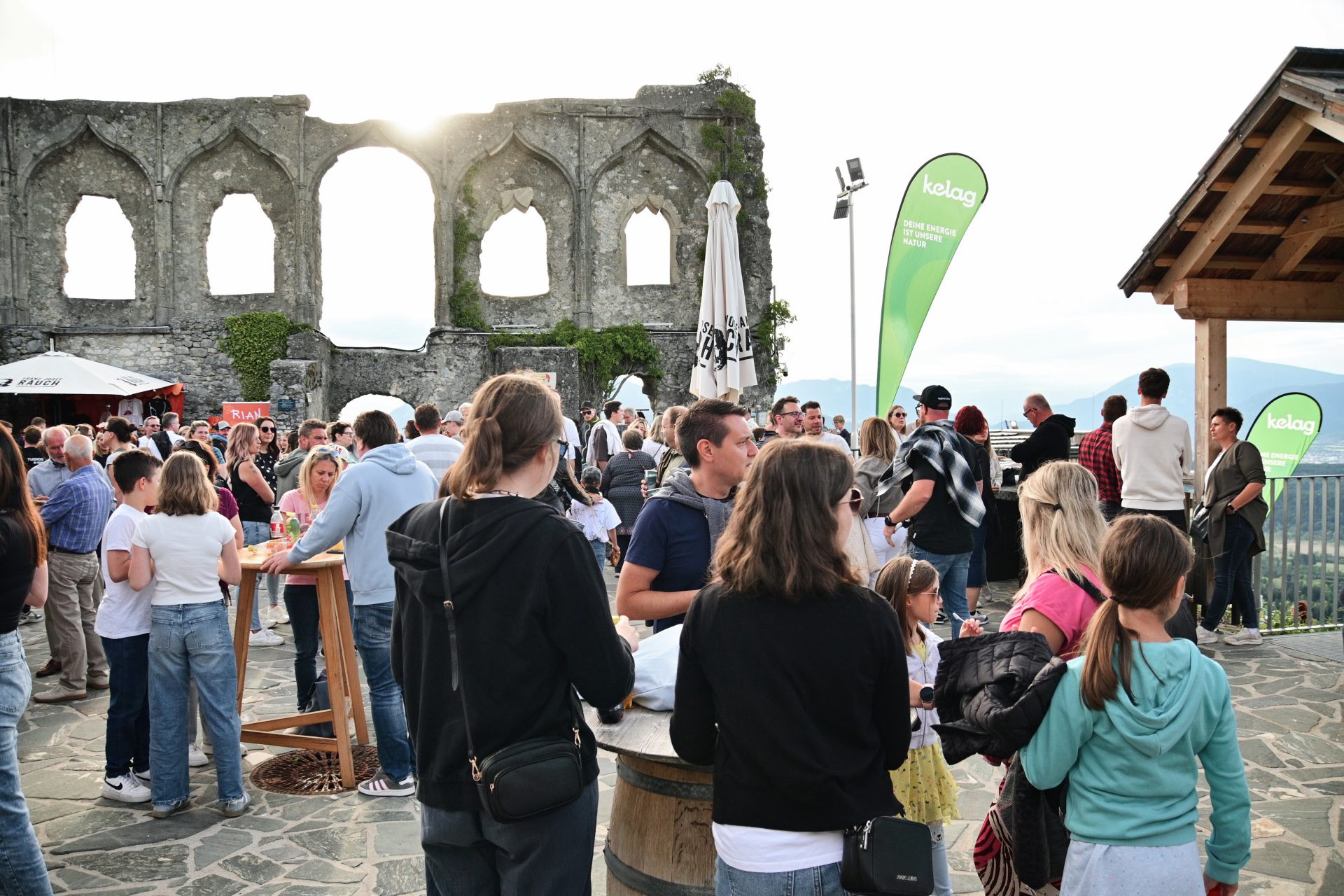 Menschenmenge vor historischen Steinruinen mit Bögen auf einer Terrasse bei einer Veranstaltung