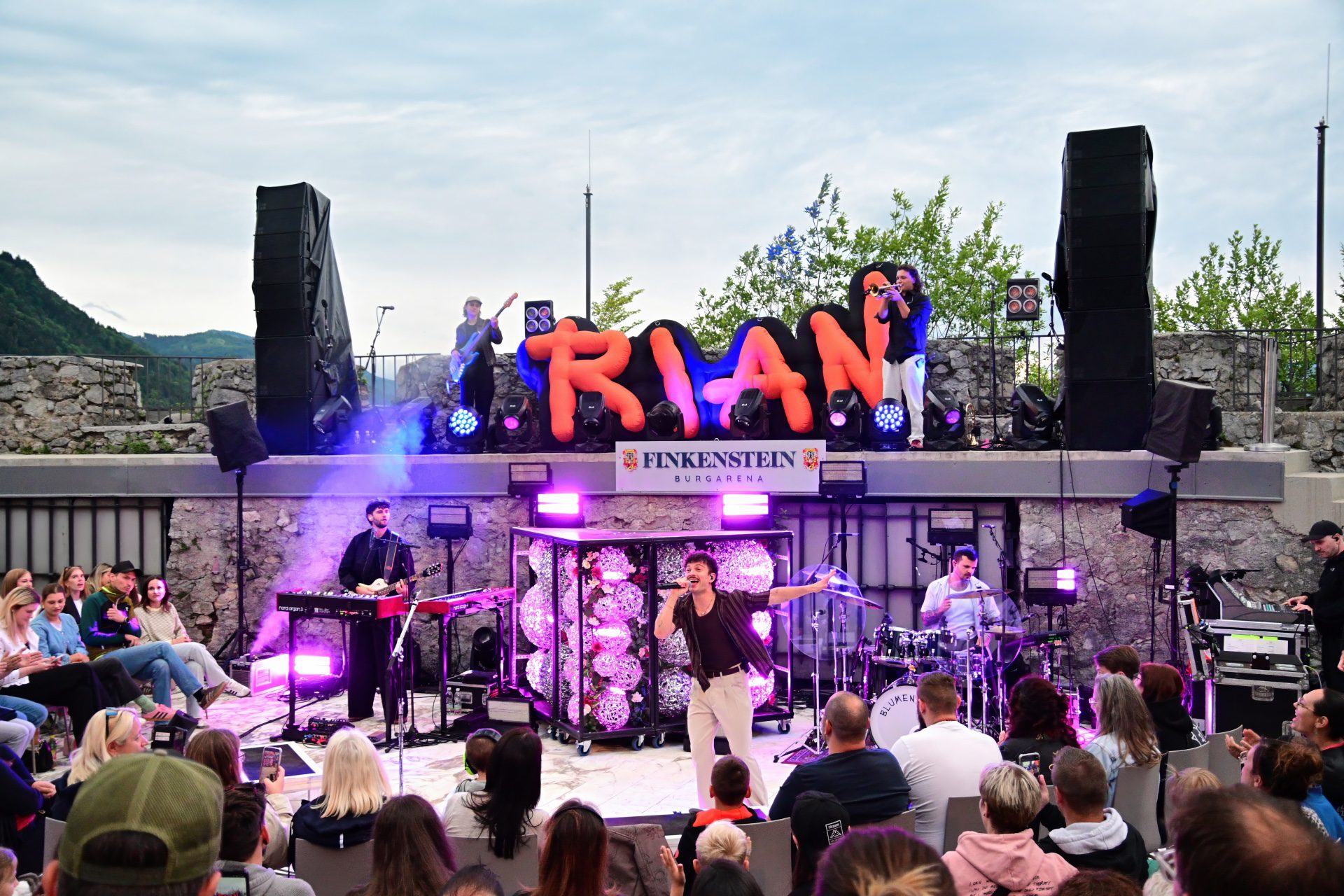 Sänger der Band Trian performt auf der Bühne vor Publikum in Finkenstein Burgarena.
