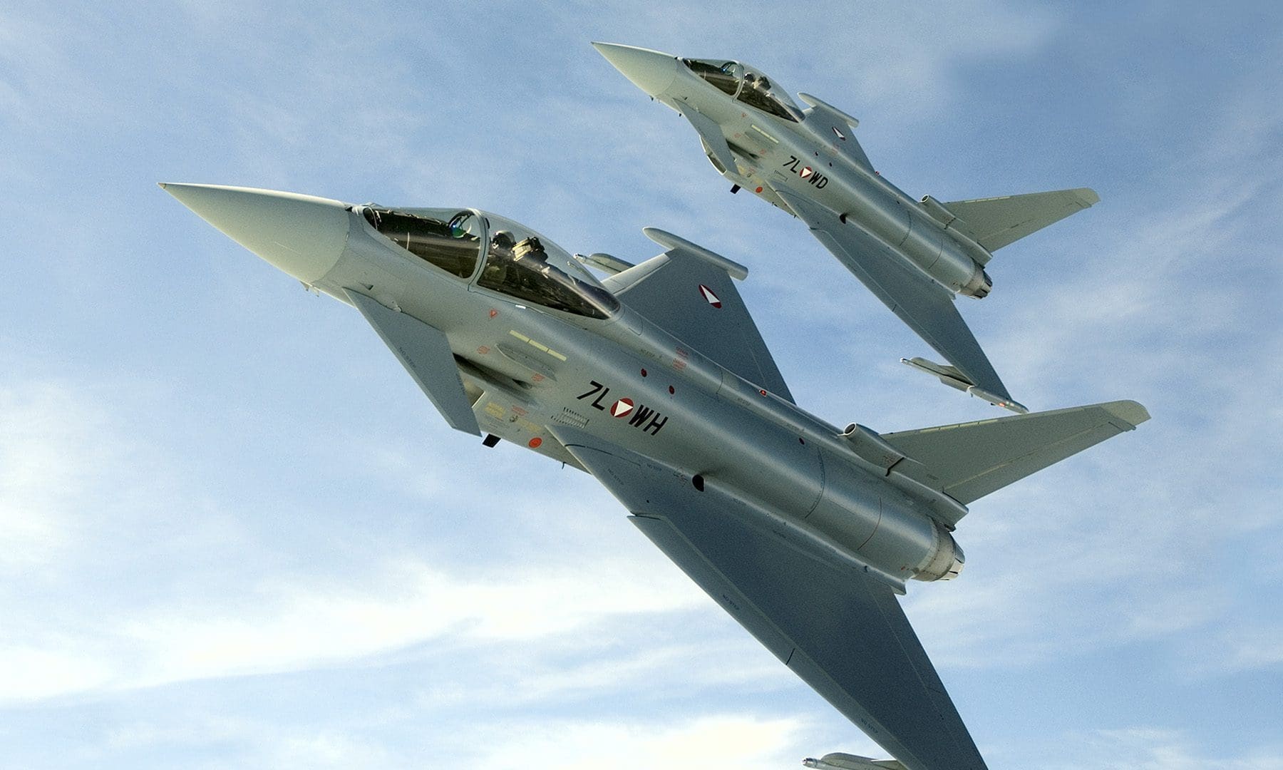 Zwei graue Eurofighter Kampfjets fliegen in Formation am blauen Himmel