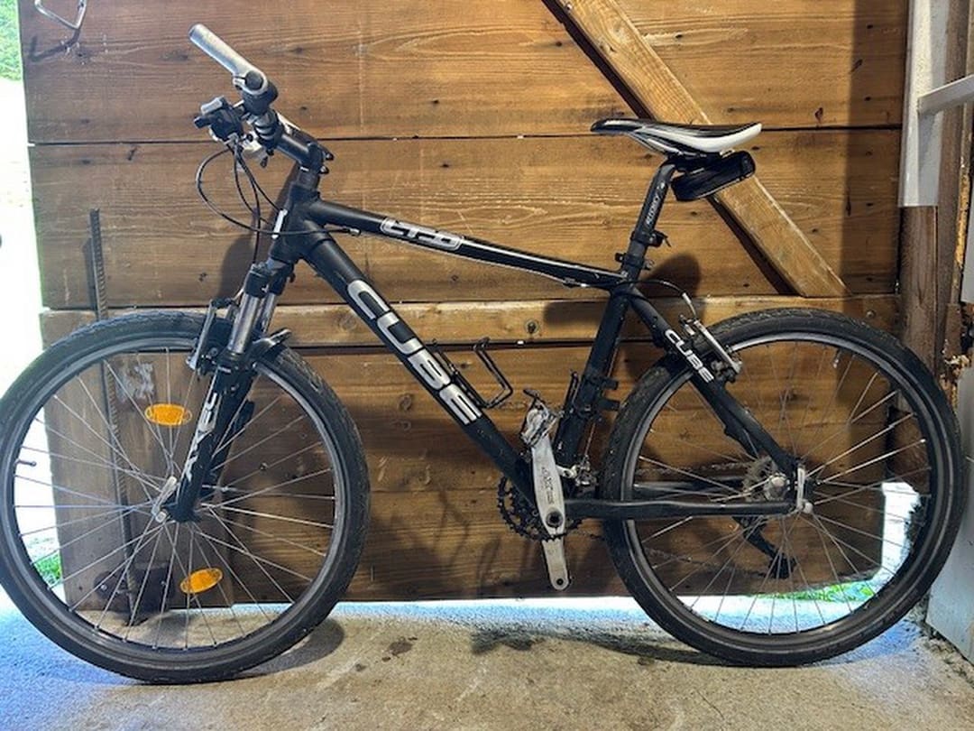 Schwarzes Mountainbike der Marke Cube an einer Holzwand