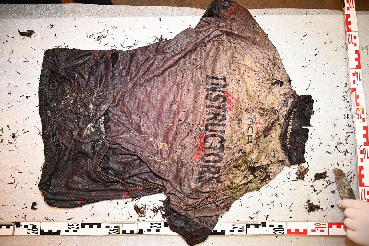 Verschmutztes Radtrikot mit Aufschrift Instructors auf weißer Messunterlage mit Maßstäben