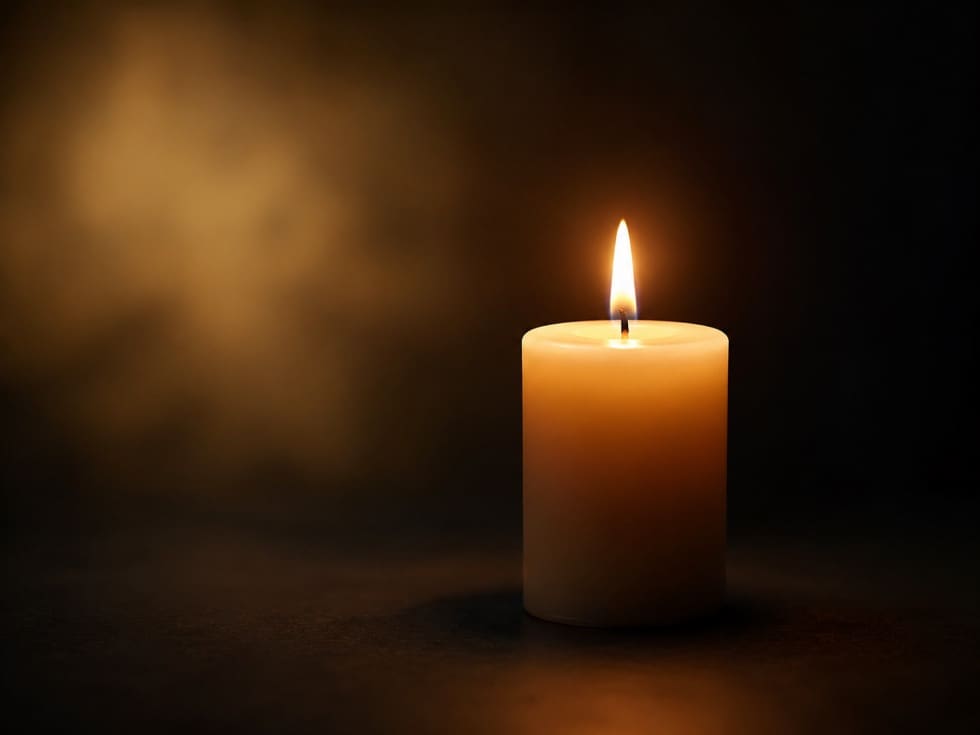 Eine brennende weiße Kerze mit heller Flamme in dunkler Umgebung