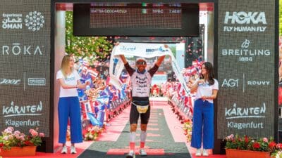 Mattia Ceccarelli präsentiert Siegerband zwischen zwei Frauen am Ziel des Ironman Austria