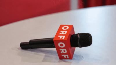 Schwarzes Mikrofon mit rotem Würfel und ORF-Logo auf weißem Tisch
