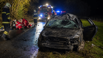 Zerstörtes Auto nach Unfall mit Rettungskräften und Verletzten auf nächtlicher Straße