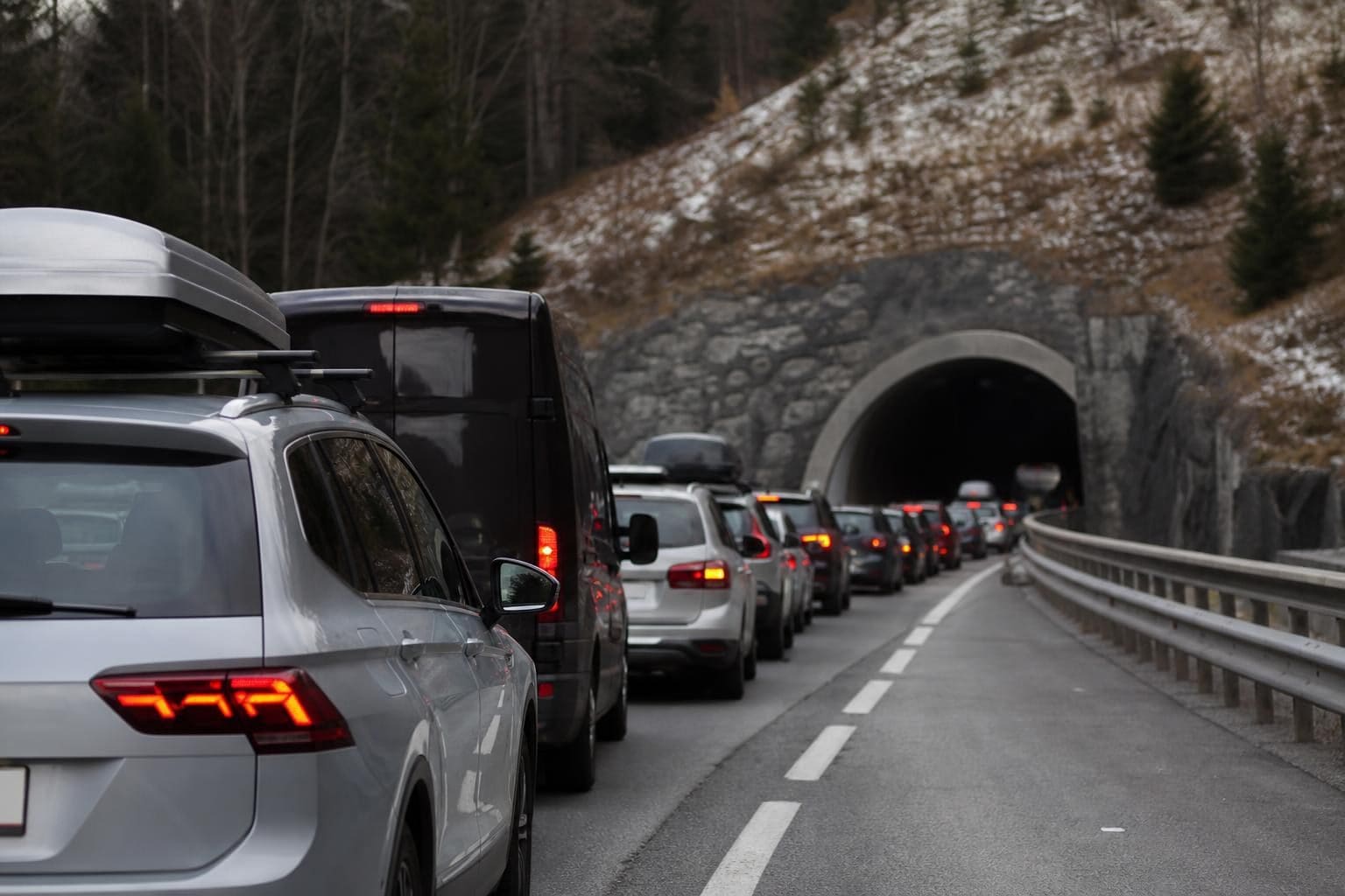 Autoschlange mit roten Rücklichtern vor dem Eingang eines Tunnels auf der Autobahn