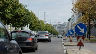 Fahrzeuge auf einer breiten Straße in Wien mit Verkehrsschildern und Bäumen am Rand