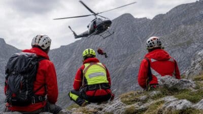Bergretter in roter Kleidung beobachten Hubschrauber bei der Bergung am Großen Pyhrgas
