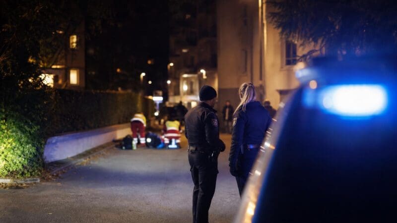 Polizisten und Rettungskräfte stehen nachts an einem Tatort mit Blaulicht