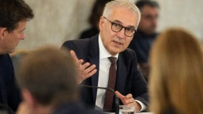 Finanzminister Markus Marterbauer mit grauem Haar und Brille gestikuliert in Anzug bei einer Sitzung