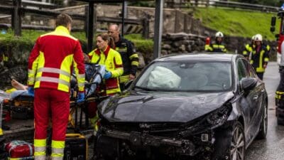 Rettungskräfte in Warnwesten versorgen Verletzte neben einem Unfallwagen an einer Haltestelle