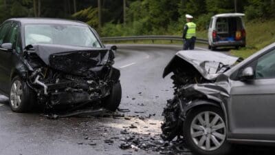 Zwei stark beschädigte Autos nach Frontalzusammenstoß auf kurviger Straße im Wald