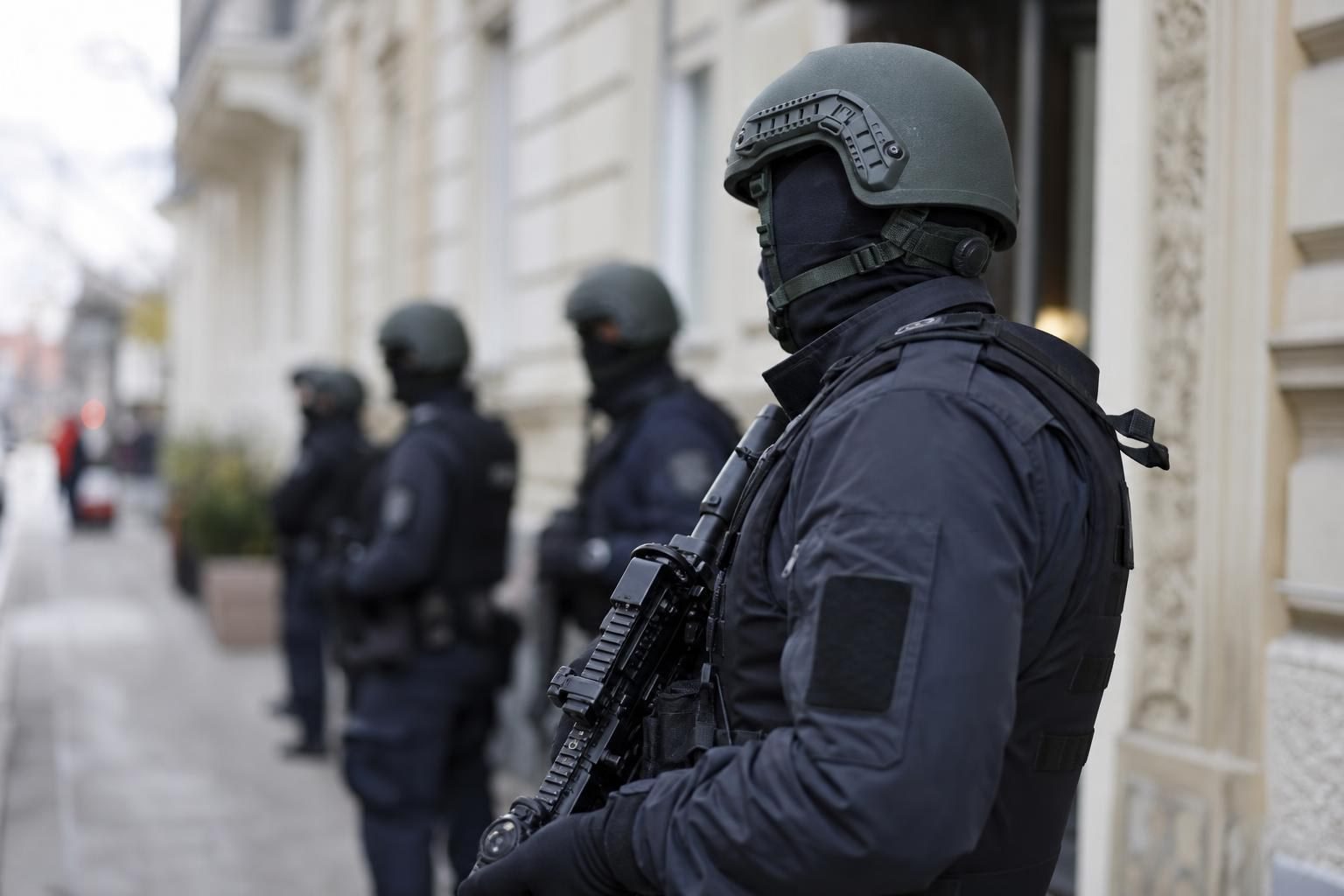 Bewaffnete Polizisten in taktischer Ausrüstung stehen vor einem Gebäude