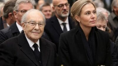 Älterer Mann mit Brille und blonde Frau in schwarzer Kleidung nebeneinander