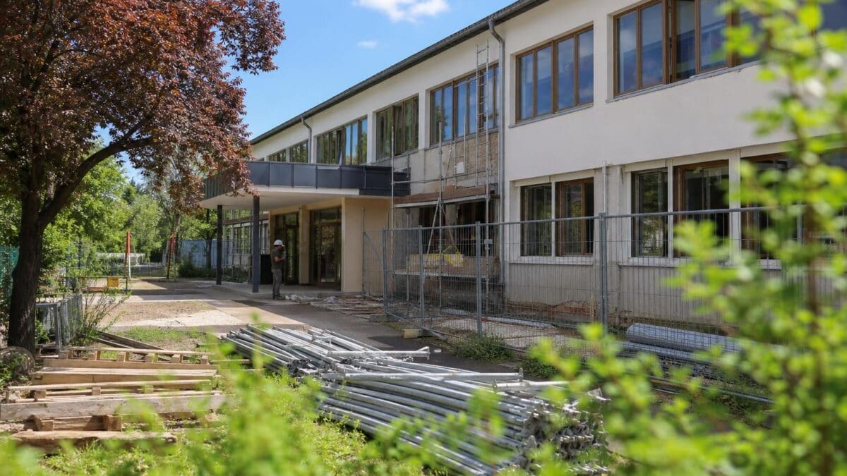 Baustelle vor einem zweigeschossigen Gebäude mit Gerüst und Metallrohren