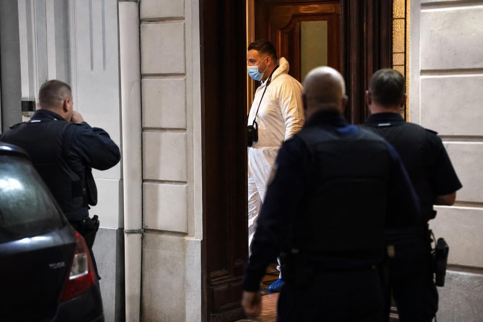 Polizisten und ein Spurensicherer in weißem Overall am Gebäudeeingang