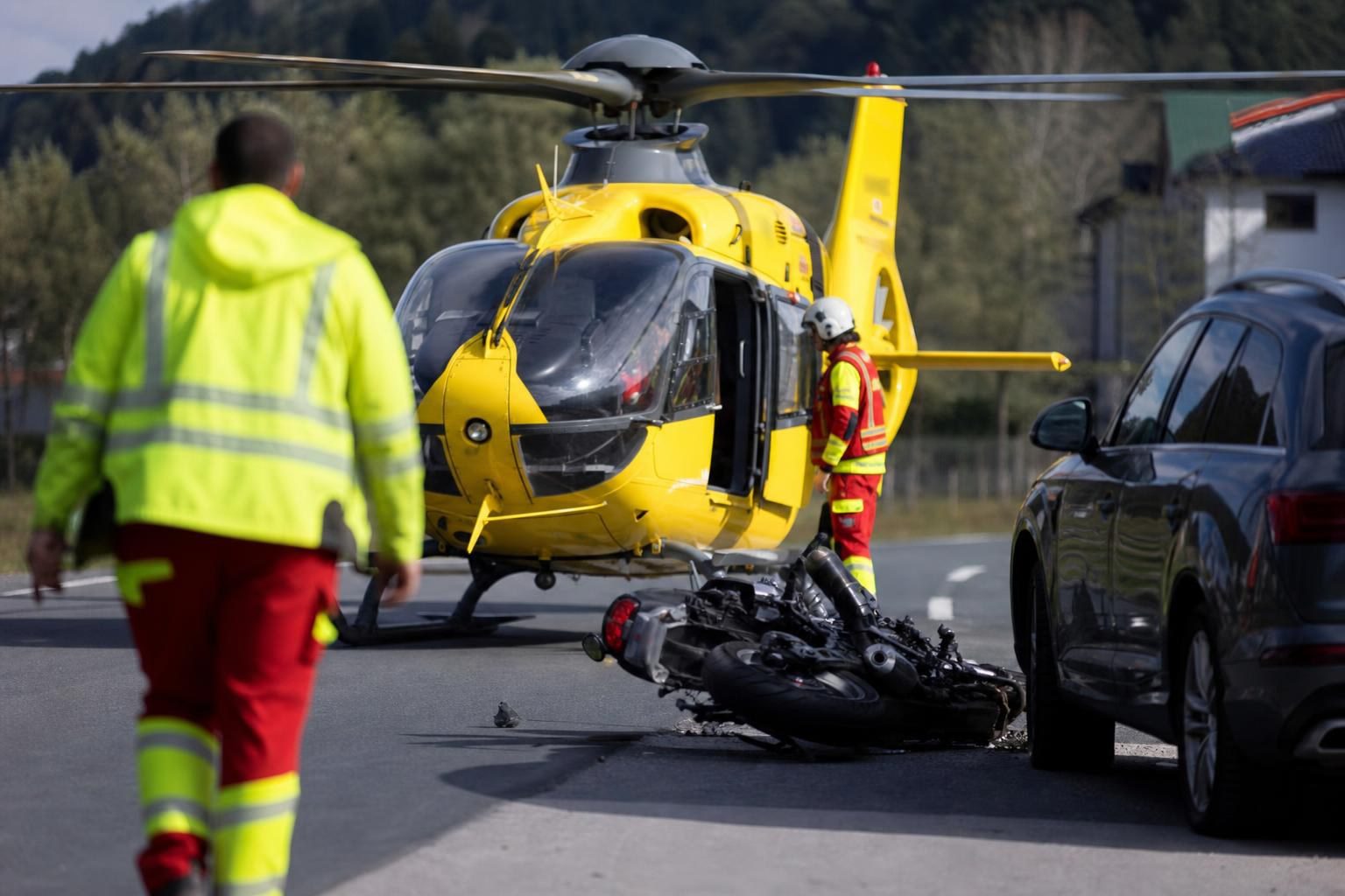 Gelber Rettungshubschrauber neben einem verunglückten Motorrad auf der Straße mit Einsatzkräften
