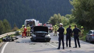 Polizisten und Rettungskräfte sichern Unfallstelle mit beschädigtem Auto und Motorrad auf der Straße