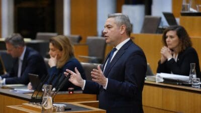 Politiker im dunklen Anzug gestikuliert am Rednerpult im Nationalrat