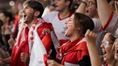 Junge österreichische Fans mit rot-weiß-roten Flaggen und Gesichtsbemalung jubeln lautstark beim Public Viewing.