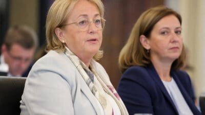 Margit Göll mit goldener Brille und hellem Blazer bei einer Sitzung