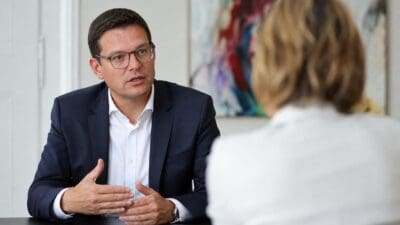 Ein Mann mit Brille im dunklen Anzug spricht an einem Tisch mit einer Frau