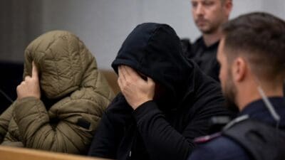 Angeklagte Männer verdecken im Gerichtssaal ihre Gesichter mit den Händen