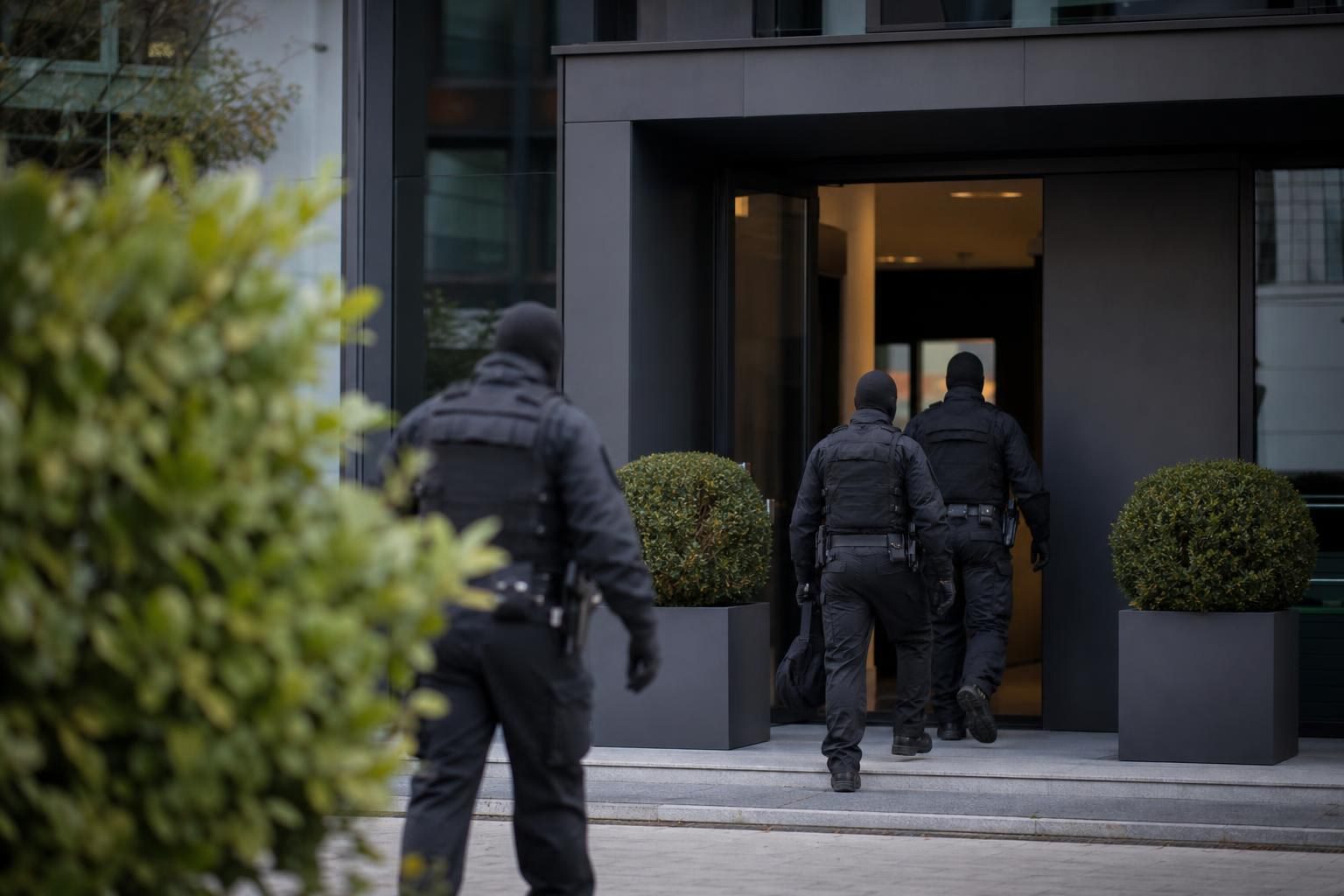 Polizisten in taktischer Ausrüstung betreten das Gebäude einer Firma während einer Razzia