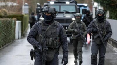 Bewaffnete Polizisten der Sondereinheit Cobra mit Gewehren vor einem gepanzerten Fahrzeug