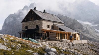 Bauarbeiter errichten Holzanbau an der Stein- und Holzhütte in den Bergen