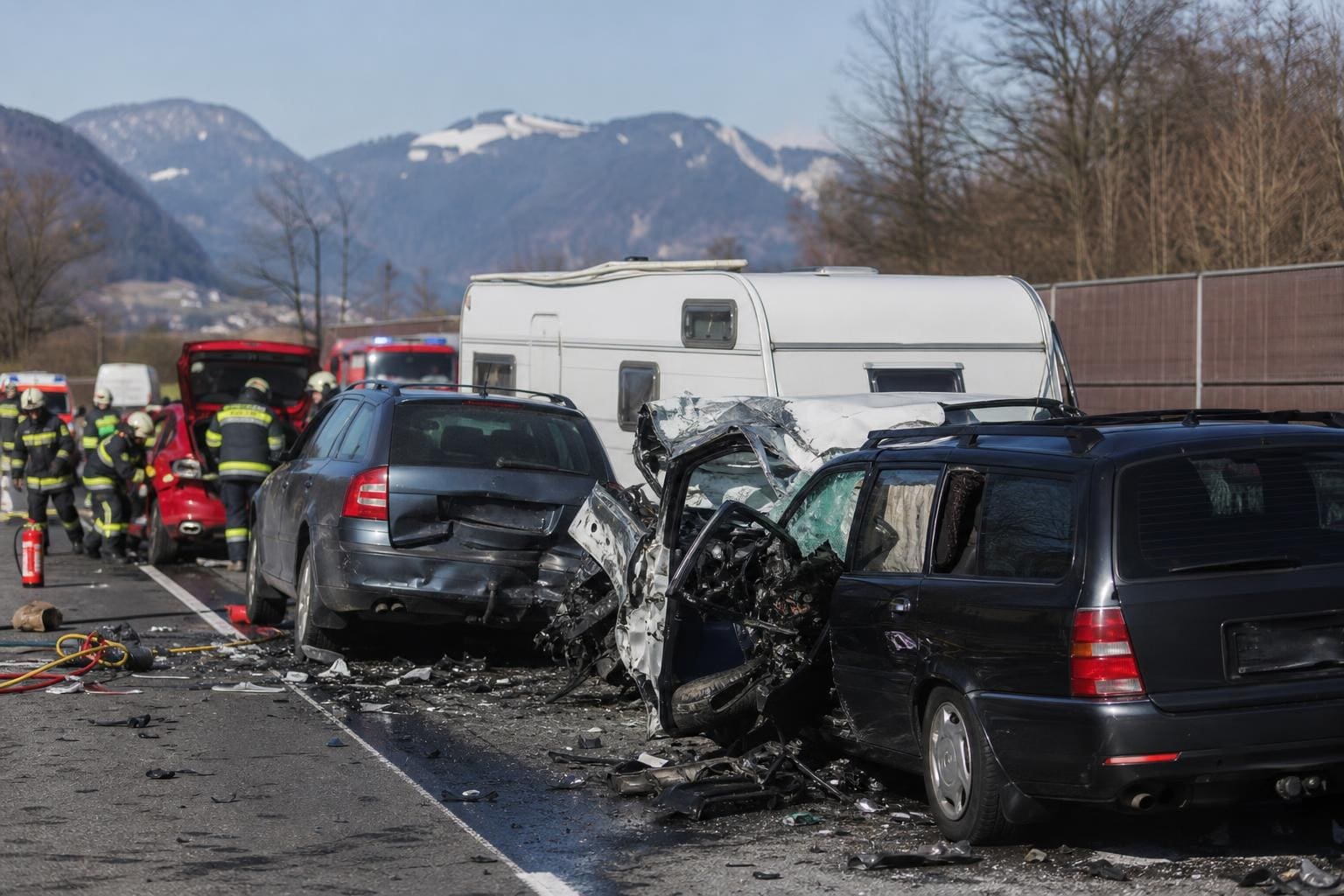 Mehrere stark beschädigte Autos und ein Wohnwagen nach einem Unfall auf der Autobahn